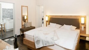A hotel room with a large bed, bedside tables, a small desk, and a dining area. - Gästehaus und Weingut Peth (Floersheim Dalsheim)