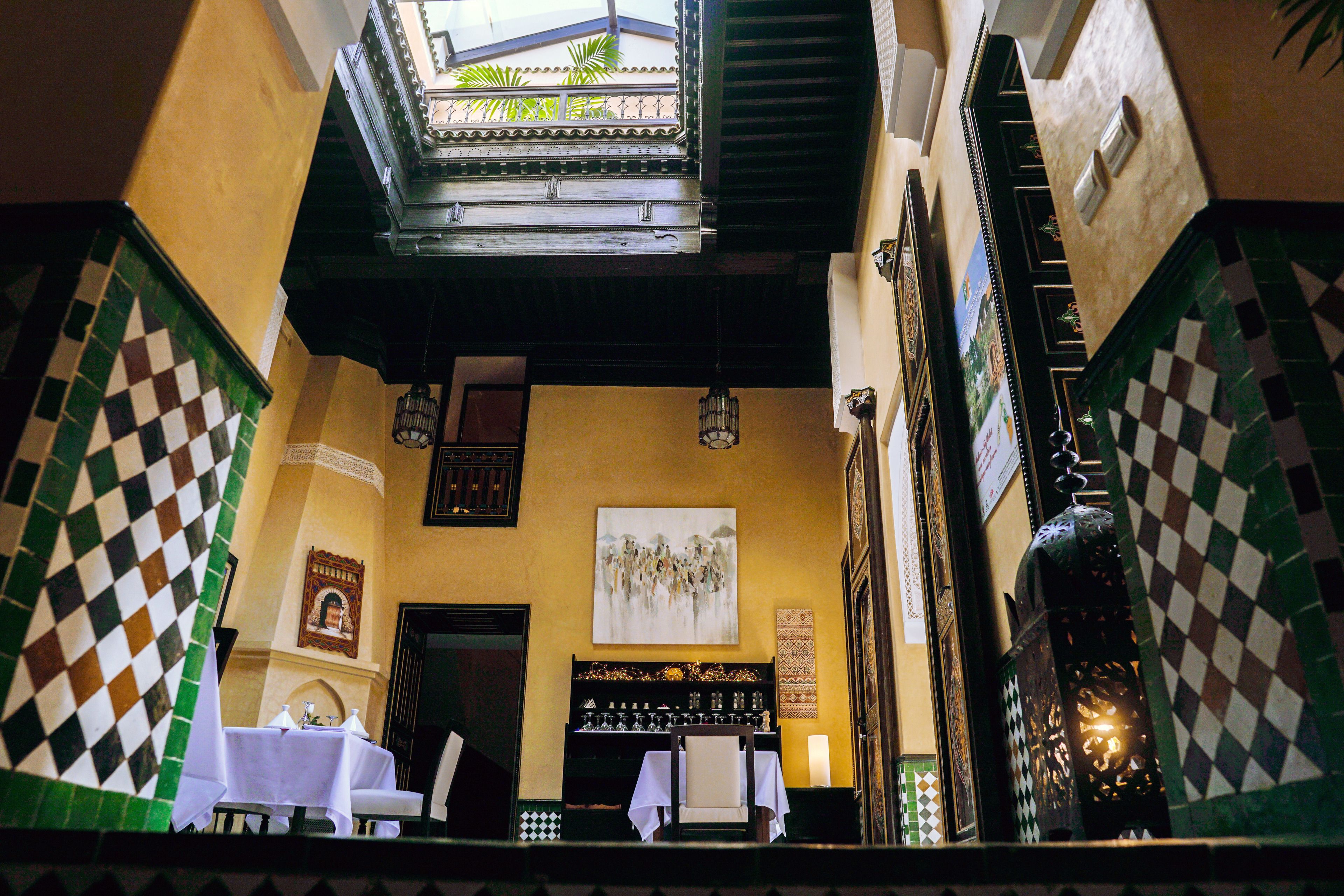 Un patio interior con zona de comedor, un mural y vistas al exterior.
