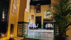 A lobby with a checkered floor, a potted plant, and a table with a white tablecloth. - Riad Zidania (Meknes)