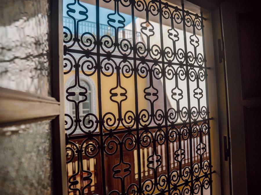 A wrought iron gate with intricate designs, likely leading to a building or property.