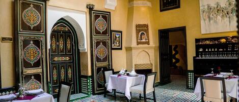 A dining area with tables set for service, ornate doors, and a patterned floor.