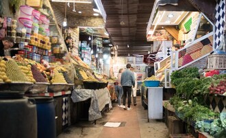 Un mercado cubierto con diversos puestos de comida y compradores.