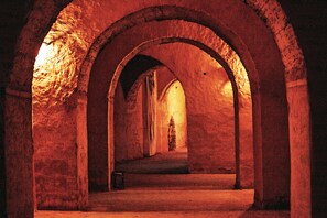 An arched corridor with stone walls and a single lantern on the floor.