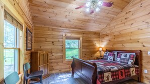 A wooden cabin bedroom with a bed, a chair, a desk, and a window. - Deep Creek Log Cabin- Motorcycle Friendly - Gas Fireplace - Covered Porch (Bryson City)