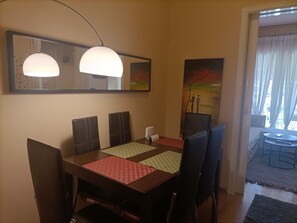 Un espace repas comprenant une table, des chaises, une lampe et des œuvres d’art accrochées aux murs.