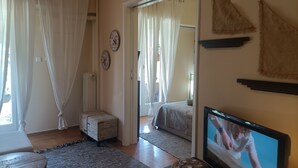 Un salon confortable avec un téléviseur, un petit pouf et un tapis.