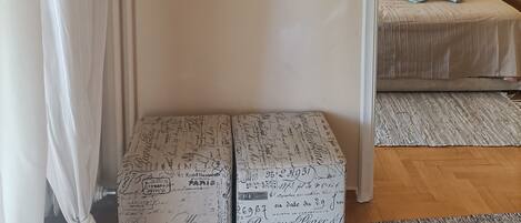Una habitación con dos relojes en la pared, una cama con colcha estampada y una mesita de noche con lámpara.