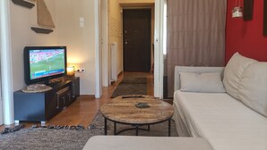 Un salon avec un téléviseur, un canapé et une table basse.