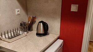 Cocina pequeña con lavamanos, hervidor y utensilios en la encimera.