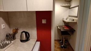 Cocina compacta con lavamanos, hervidor y utensilios.
