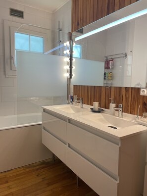 Een bad/douchecombinatie, een haardroger, handdoeken, zeep
