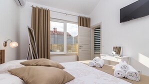 A bedroom with a bed, a bedside table, a mirror, a TV, and a window with curtains. - Villa Sunny Home in Galizana (Galizana)