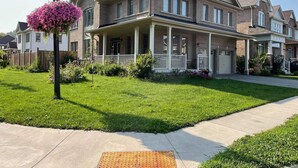 A two-story residential house with a front porch, brick exterior, and a well-maintained lawn. - A BEAUTIFUL & SPACIOUS 4 BEDROOM VACATION HOME (Niagara Falls)
