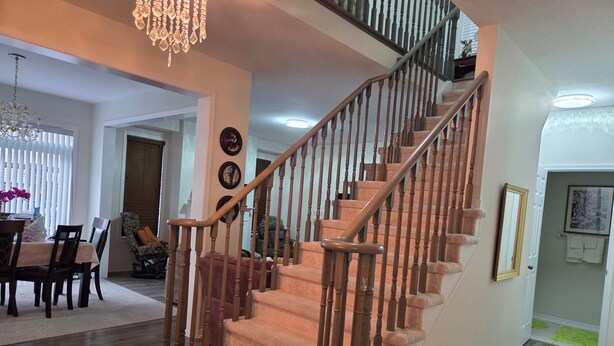 A staircase with wooden balusters and carpeted steps, leading to an upper floor. - A BEAUTIFUL & SPACIOUS 4 BEDROOM VACATION HOME (Niagara Falls)