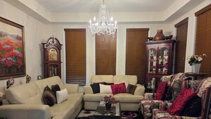 A living room with two sofas, a coffee table, a chandelier, and a cabinet with decorative items. - A BEAUTIFUL & SPACIOUS 4 BEDROOM VACATION HOME (Niagara Falls)