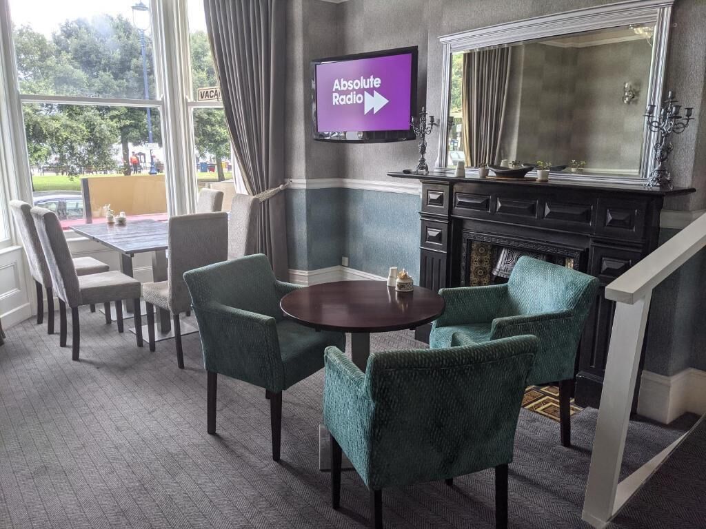 Ett hotellrum med en matplats, en öppen spis och en tv som visar kanalen ”Absolute Radio”.