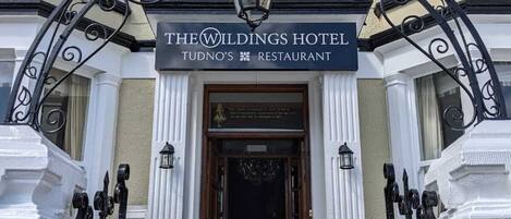 The entrance to The Wildings Hotel with a sign above the door.