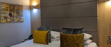 Una habitació d'hotel amb un llit gran, dues làmpades de nit, un telèfon i una obra d'art penjada a la paret.