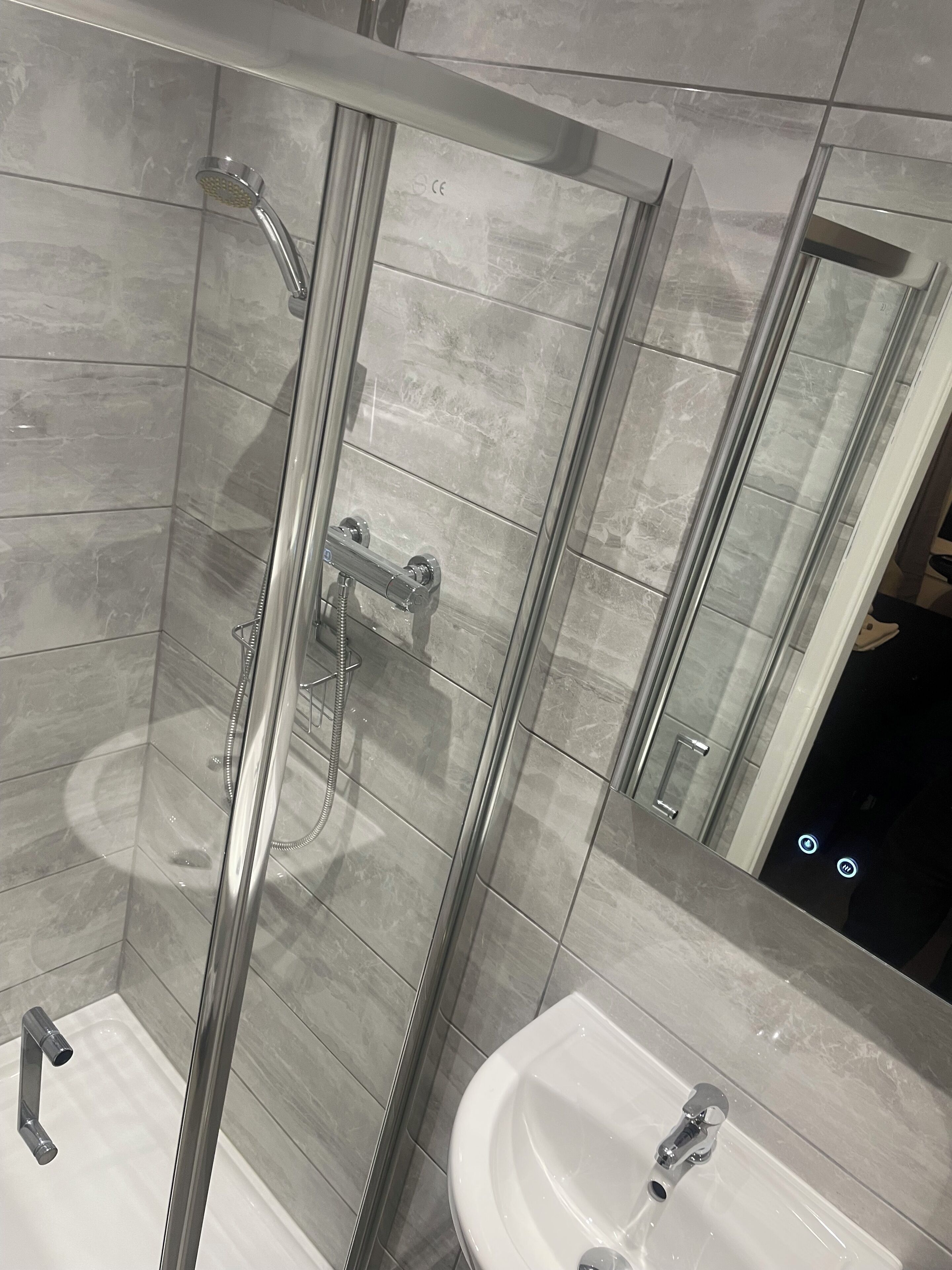 Ein modernes Badezimmer mit einer Duschkabine, einem Waschbecken und einem Spiegel.