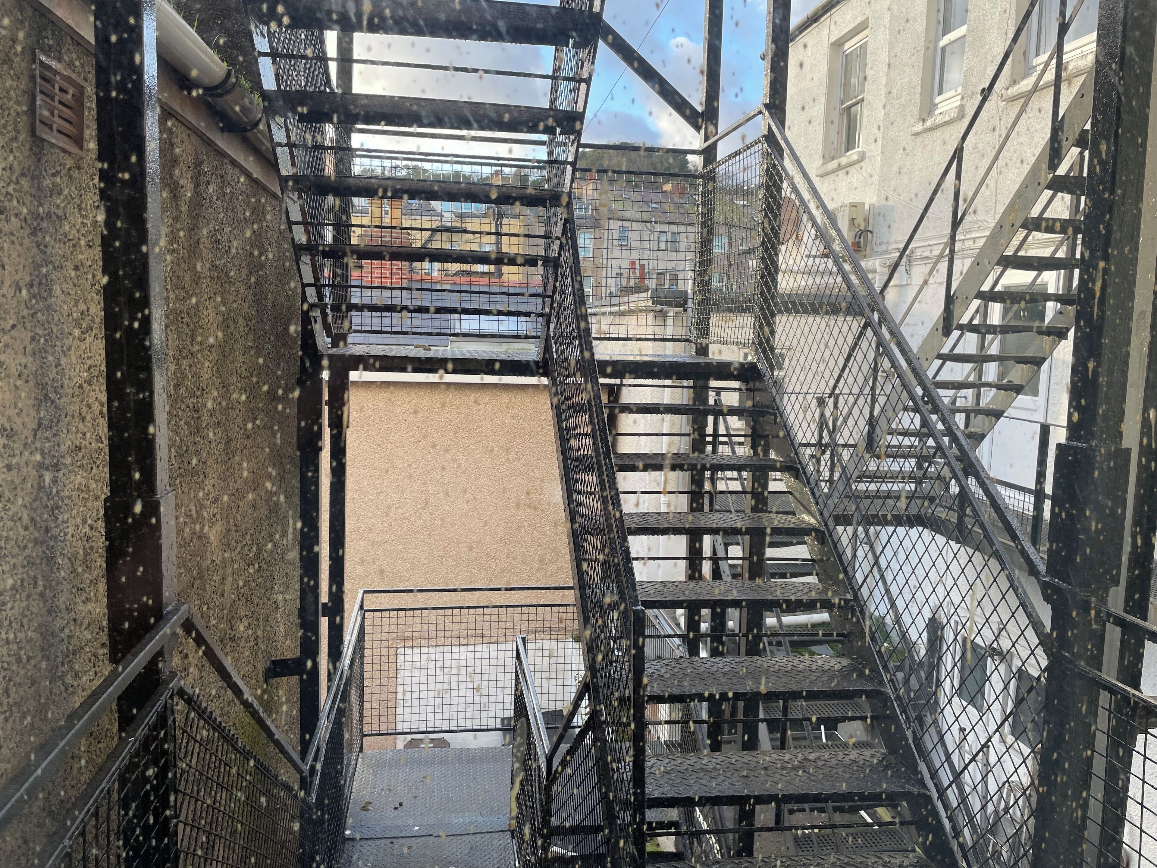 A metal fire escape with a metal railing and a metal door at the bottom.