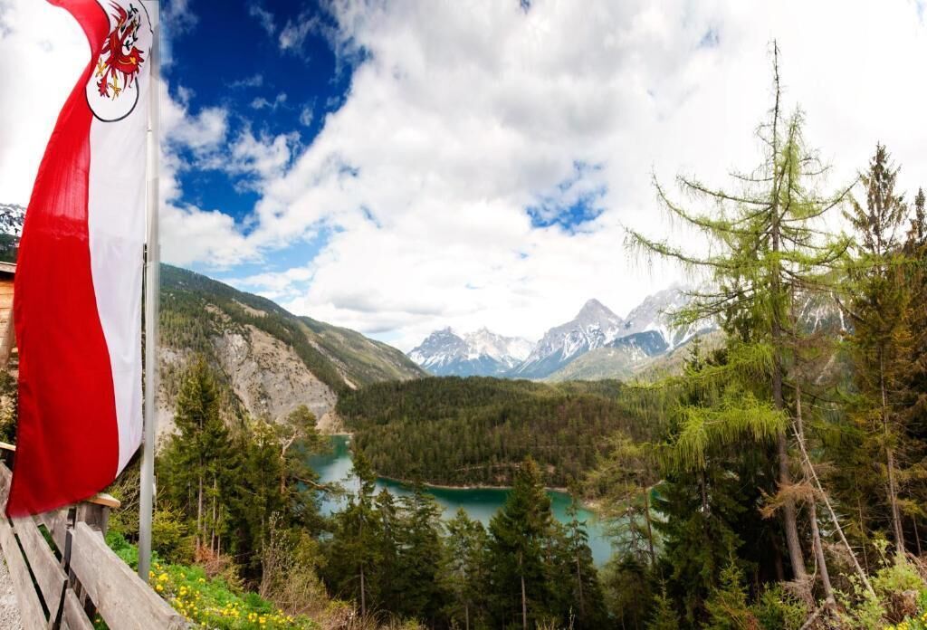 Un paisaje montañoso con un lago, una bandera y una estructura de madera.