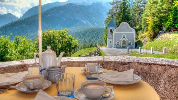 A table set for breakfast with a view of a mountain landscape and a small church. - Alpenretreat (Nassereith)