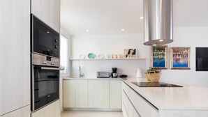 Eine moderne Küche mit integrierten Geräten, einer weißen Arbeitsplatte und einer Edelstahl-Dunstabzugshaube.