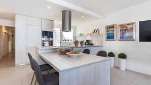 Eine moderne Küche mit hellen Holzschränken, einer Edelstahl-Dunstabzugshaube und einem Essbereich mit einem Holztisch und Stühlen.
