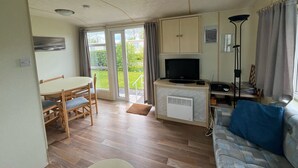 A compact living space with a dining area, a sofa, a television, and a small kitchenette.