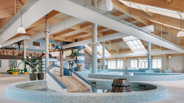 A spacious indoor swimming pool area with multiple lanes, a central slide, and a seating area with chairs and tables.