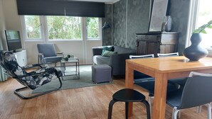 A modern living room with a wooden dining table, grey sofa, and a black lounge chair. - CS 48 - Callassande Vacation Park (Callantsoog)