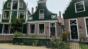 A row of traditional houses with green facades and white trim, featuring brickwork and a small garden with a fence. - CS 48 - Callassande Vacation Park (Callantsoog)