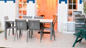 A two-story building with a balcony, a dining area with chairs and a table, and a grill outside. - Cottage 40 Beach Golf Surf (Moliets-et-Maa)