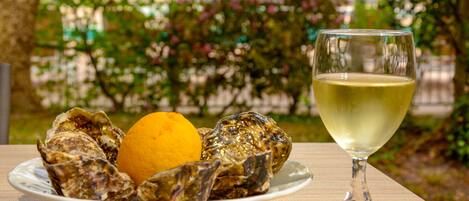 A plate of oysters with a lemon wedge and a glass of white wine on a table.