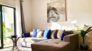 Una sala de estar moderna con un sofá color beige, una mesa de centro y un florero con orquídeas blancas.