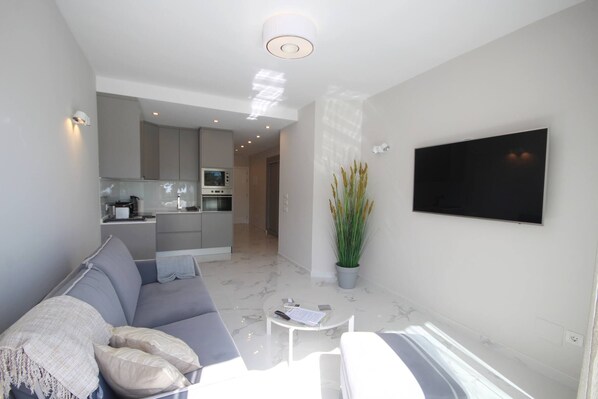 Una sala de estar moderna con un sofá gris, una mesa de centro y un televisor de pantalla plana montado en la pared.