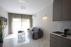 Una sala de estar moderna con un sofá, una mesita redonda y una cocina con armarios y encimera.