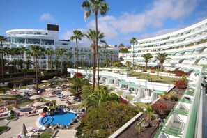 Un resort con piscina, palmeras y un gran edificio de hotel.