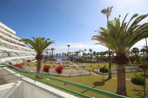 Un resort con zona de piscina, palmeras y vista al océano.