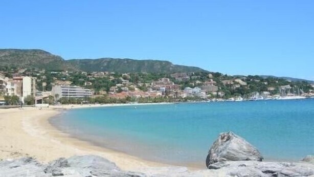 A coastal view with a sandy beach, clear blue water, and a rocky outcrop in the foreground. - Duplex with 3 rooms in a quiet neighbourhood (Var)