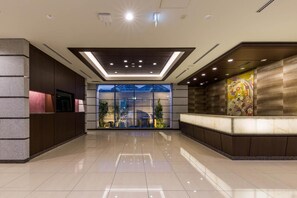 A modern lobby with a glass entrance, a reception desk, and a large window. - N Gate Hotel Osaka (Tajiri)