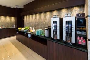 A hotel reception area with a counter, a beverage dispenser, and a small salad display. - N Gate Hotel Osaka (Tajiri)
