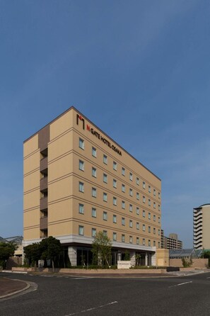 Ein mehrstöckiges Hotel mit schlichter Fassade, zahlreichen Fenstern und einem Schild, das es als N Gate Hotel Osaka kennzeichnet.