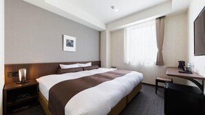 A hotel room with a large bed, a desk, a chair, a bedside table with a lamp, a picture on the wall, and a window with curtains. - N Gate Hotel Osaka (Tajiri)