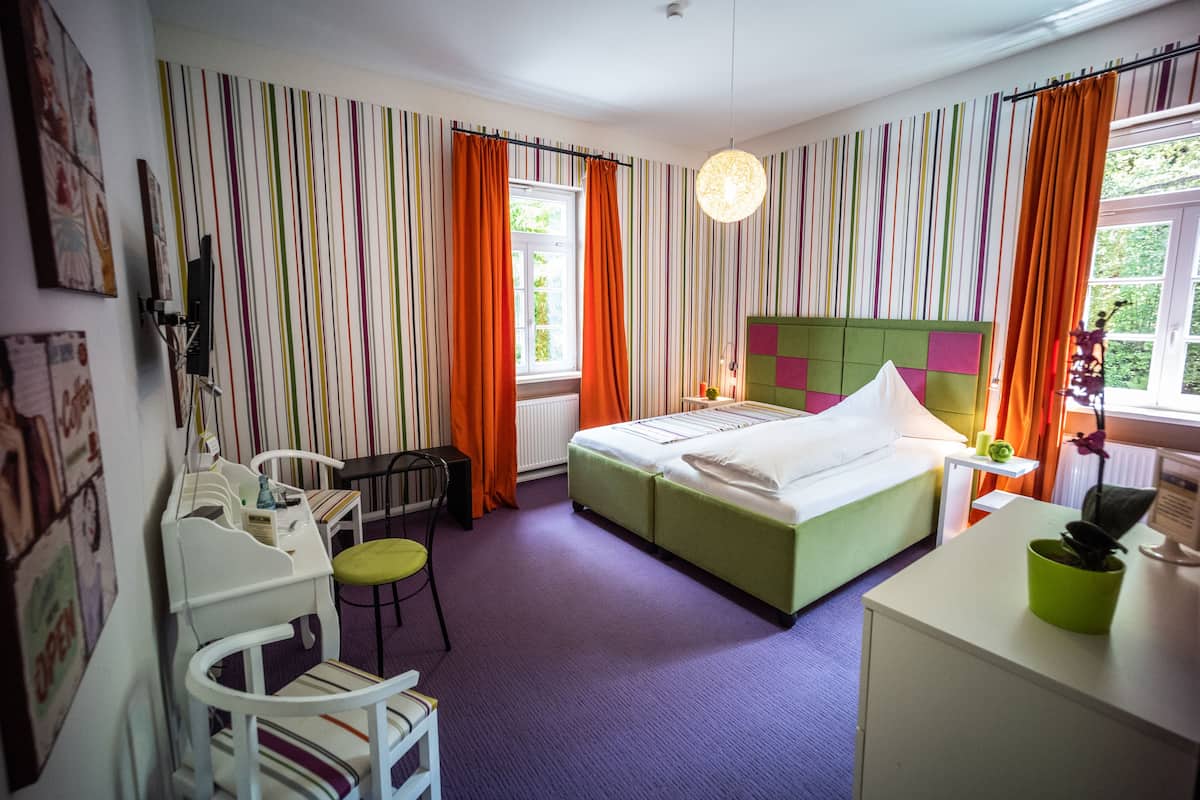 A room with a bed, a desk, a chair, and a window with curtains.