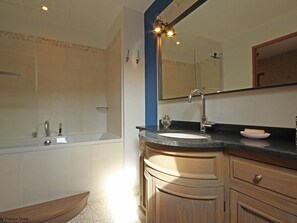 A bathroom with a bathtub, a sink, and a vanity with drawers.