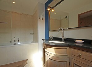A bathroom with a bathtub, a sink, and a vanity with drawers.