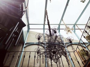 A metal chandelier with a complex design, hanging from a glass ceiling structure. - Sennong Homestay (Tainan)