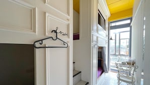 Un couloir avec une porte blanche, un porte-manteau noir et un escalier menant à une pièce avec vue.