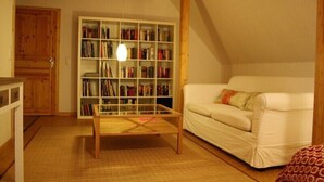 Una sala de estar acogedora con un sofá blanco, una mesa de centro de madera y una estantería llena de libros.
